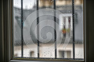 Conceptual image of a window on a rainy day: close-up image of the glass with rain drops, in the background blurred the view of