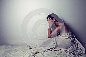 Conceptual image of a woman sad and lone on a bed under a sheet