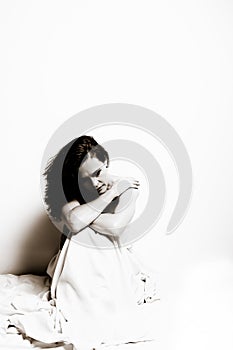 Conceptual image of a woman sad and lone on a bed under a sheet