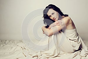 Conceptual image of a woman sad and lone on a bed under a sheet