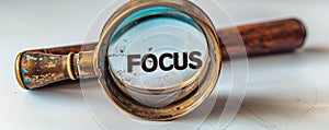 Conceptual magnifying glass focusing on the word FOCUS isolated on a white background, symbolizing clarity, concentration