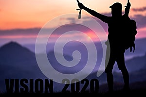 Conceptual message writing showing `vision 2020`. The young mountaineer managed to climb to the top and achieve his goal.