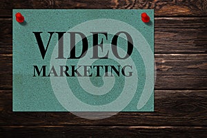 Conceptual messages `VIDEO MARKETING` written on green paper stands as an advertisement on a wooden surface.