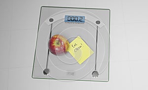 Conceptual and modern still life delicious apple and yellow posit note text saying eat clean stuck on bathroom scale in weight photo