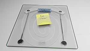 Conceptual and modern still of yellow handwritten posit note saying eat clean stuck on bathroom scale in weight loss dieting and photo