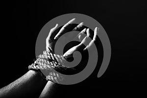 Conceptual monochrome image of woman hands tied with a coarse rope