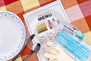 Conceptual of the new normal lifestyle with usage of sanitizer, face mask, gloves and disposable menu at restaurant