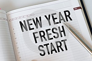 Conceptual, notebook on a white table. open diary and pen with new year...fresh start words