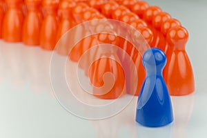 Conceptual orange game pawns and a blue play pawn