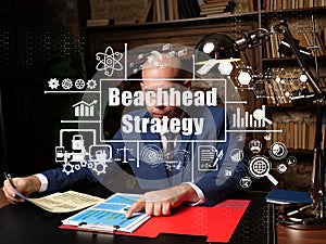 Conceptual photo about Beachhead Strategy with written phrase. Cheerful young businessman working at desk in office on background