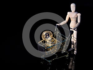 Conceptual photo of cryptocurrency. Bitcoin in a consumer basket held by a small wooden man.