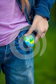 Conceptual photo of girl putting globe in pocket