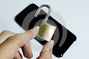 Conceptual photo of security on mobile phones. Hand holding a open padlock and a cell phone in the background