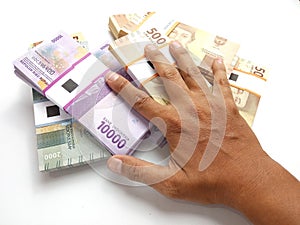 Conceptual Photo, Top View, Hand Holding Packs of Rupiah Indonesia Money, 2000, 5000, 10000, at white background