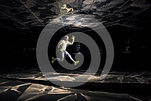 Conceptual photo of young and attractive man in jump on black background.