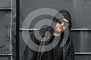 Conceptual photo of young and serious rapper in black zipped jacket.