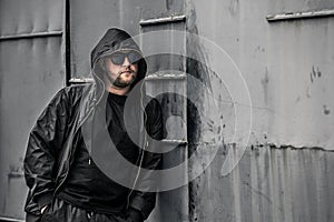 Conceptual photo of young and serious rapper in black zipped jacket.