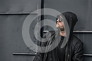 Conceptual photo of young and serious rapper in black zipped jacket.
