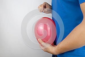 Conceptual photography. The man holds a red ball near his belly, which symbolizes bloating and flatulence. Then he brings a needle