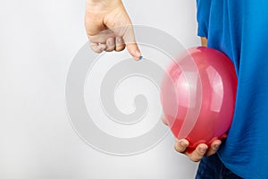 Conceptual photography. The man holds a red ball near his belly, which symbolizes bloating and flatulence. Then he brings a needle