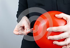 Conceptual photography. The woman holds a red ball near his belly, which symbolizes bloating and flatulence. Then she brings a nee