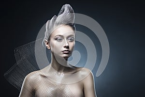 Conceptual portrait of beautiful naked shoulders vanguard hairstyle metallic colour hair girl wearing steel construction armature