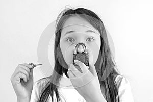 Conceptual portrait of a child keeping silence with lock over her mouth and a key to the lock in your hand. caucasian