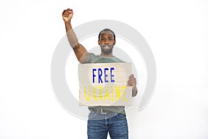 Conceptual portrait of emotional young dark skinned man shouting, holding poster with lettering Free Ukraine isolated on