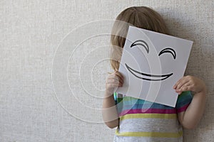 Conceptual portrait smiley. A small child covers his face with a funny mask. smiley.