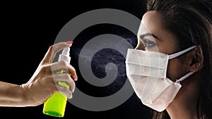 Conceptual portrait of a woman wearing hygienic mask and looking at the antibacterial spray photo