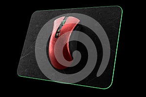 Conceptual red gaming mouse on professional pad isolated on black blackground