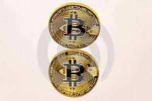 Conceptual representation of a gold bitcoin on a white mirror surface.