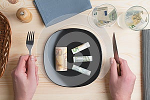Conceptual studio shot of dinner table with euro bank notes on the plate instead of food. Concept for rising food prices