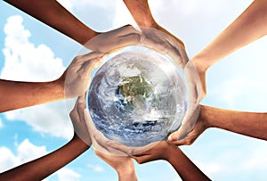 Conceptual symbol of multiracial human hands surrounding the Earth globe. Unity, world peace, humanity concept. World environment