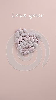 Conceptual text Love Your and symbol Heart made of pills on pink background. Creative shot for Health care, Pharmacy