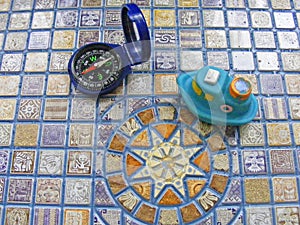 Conceptual travel toy ship and compass on mosaic background