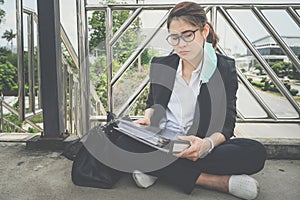 Asian unemployed businesswoman sitting on footbridge, stressed after laid off from work because impact from covid-19 pandemic outb