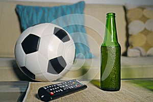 Conceptual watching football game at sofa on television with beer bottle and popcorn bowl in friends enjoying soccer game TV