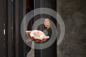 Conceptual woman hand reaching out from metal bars