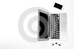Conceptual workspace or business concept. Laptop computer with mobile cellular phone and black paper clips on white background. To