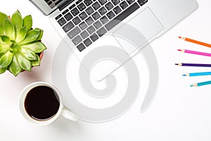 Conceptual workspace or business concept. Laptop computer with plant in a pot, cup of coffee and colorful pencils on white backgro