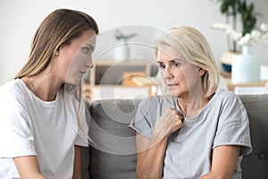 Concerned aged mom and adult daughter talk at home photo