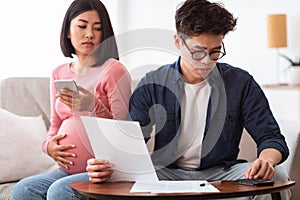 Concerned Asian Couple Calculating Expenses Looking At Bills At Home