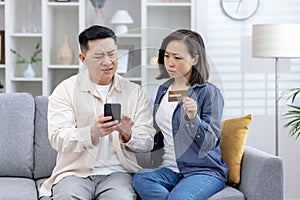 Concerned Asian couple discovering unauthorized transactions on credit card photo