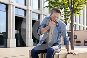 Concerned businessman sitting outside office, mature man in casual attire reflecting