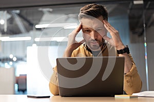 Concerned Businessman Using Laptop Having Problem Sitting In Modern Office