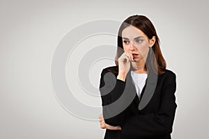 Concerned businesswoman biting her fingernail while deep in thought