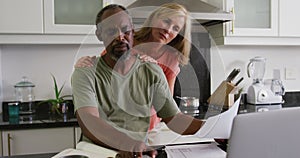 Concerned diverse senior couple using laptop computer paying bills in kitchen