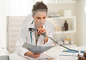 Concerned doctor with fluorography holding phone