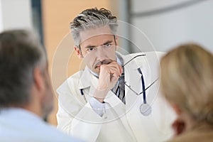 Concerned doctor meeting couple at hospital